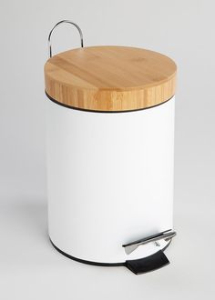 a white container with a wooden lid and handle on the side, sitting next to a cutting board