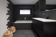 a black and white bathroom with a large mirror above the bathtub that has two wicker baskets in front of it