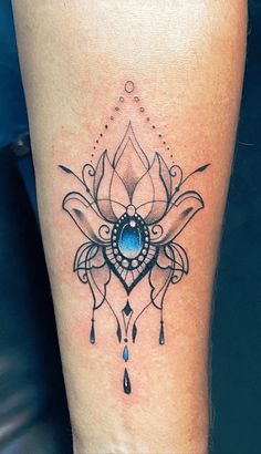 a woman's leg with a tattoo on it and a blue stone in the center