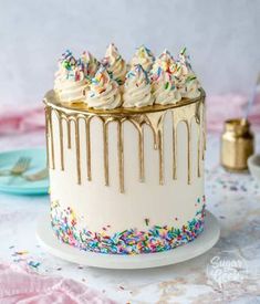 a cake with white frosting and sprinkles sitting on top of a table