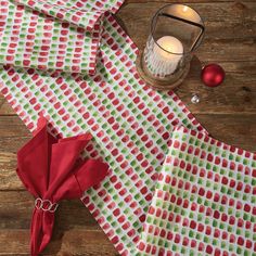 folded napkins with red and green polka dots on them next to a lit candle