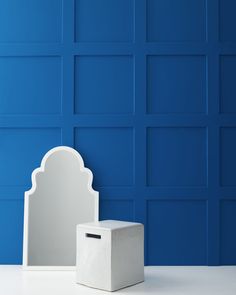 a white box sitting on top of a table next to a blue wall and mirror