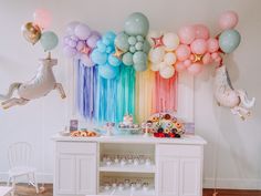 a rainbow themed birthday party with balloons, cake and cupcakes