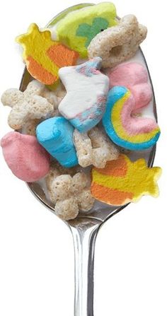 a spoon filled with marshmallows and other candy items on top of it