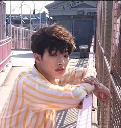 a young man leaning against a fence