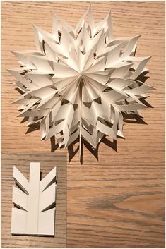 a paper snowflake sitting on top of a wooden table next to a cut out piece of paper