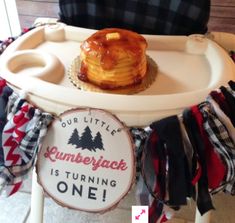 a bundt cake sitting on top of a white tray next to a sign that says our little lumber is turning one