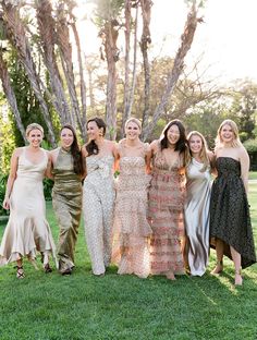 a group of women standing next to each other on top of a lush green field