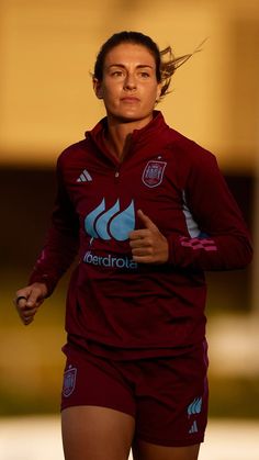 a female soccer player is running on the field with her head tilted to the side