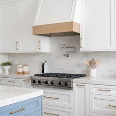 a kitchen with white cabinets, blue and gold counter tops and an oven hood over the stove