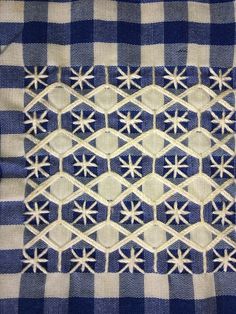 a blue and white checkered table cloth with small flowers on the edge, stitched together