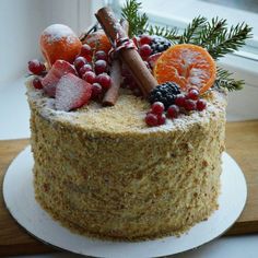 a frosted cake with fruit and spices on top sits in front of a window