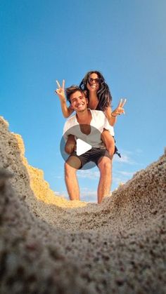 a man carrying a woman on his back in the sand