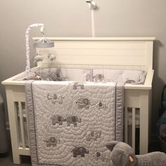 a baby crib with a teddy bear next to it and an elephant toy on the floor