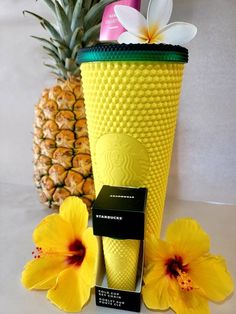 a pineapple is next to a yellow vase with flowers and a carton of shampoo