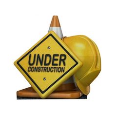 a yellow construction sign sitting on top of a hard hat next to a traffic cone