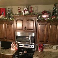 a kitchen decorated for christmas with lights and decorations on the counter top, along with wooden cabinets