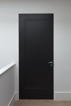 an empty room with a black door and white walls