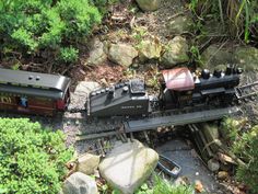 an overhead view of a toy train on the tracks near rocks and trees in the woods