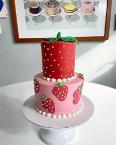 a three tiered cake decorated with strawberries and polka dots on a white table