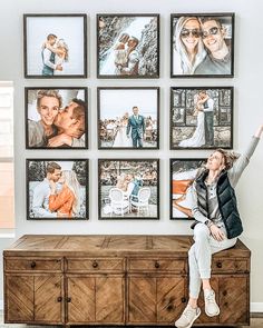 a woman sitting on top of a dresser in front of pictures hanging on the wall