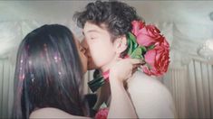 a man and woman kissing each other with flowers in their hair