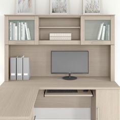 a computer desk with a monitor, keyboard and bookshelf on top of it