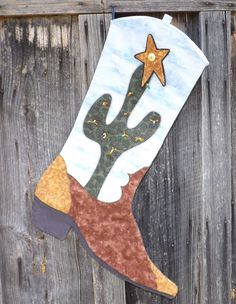 a christmas stocking hanging on the side of a wooden fence with a cactus and star