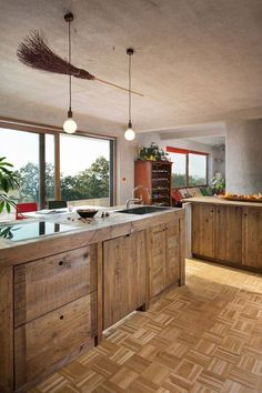 a kitchen with wooden cabinets and an island in front of large windows that overlook the trees outside