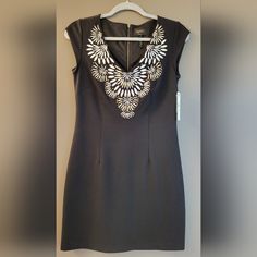 This Is An Absolutely Stunning Little Black Dress With Beautiful Embroidery And Gold-Tone Embellishments At The V-Neckline. The Dress Is Lined And Has A Zipper On The Back. It Would Be Perfect For Cocktail Parties Or Slightly More Formal Events. New, Never Worn. Comes With Tags And 4 Extra Studs. Measurements Bust: 16" Waist: 14.5" Hip: 17" Length: 33" Shoulder To Hem Zipper Length: Approx. 21" Size: 4 Us Color: Black Material: 70% Rayon / 27% Nylon / 3% Spandex | Lining: 100% Polyester Fitted V-neck Dress With Embroidered Neckline, Elegant V-neck Dress With Embroidered Neckline, Formal V-neck Dress With Floral Embroidery, V-neck Embroidered Dress With Embroidered Neckline, Embroidered V-neck Dress, Formal Embroidered V-neck Dress, Formal Fitted Dress With Embroidered Neckline, Fitted V-neck Embroidered Dress With Floral Details, Fitted Black Dress With Embroidered Neckline