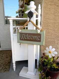 a welcome sign sitting on top of a white chair next to a potted plant