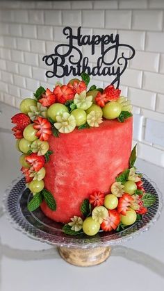 a watermelon and grapes birthday cake on a plate