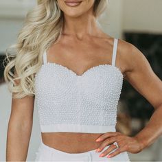 This White Bustier Crop Top Lends A Classic Look With Modern Flair. Featuring Adjustable Spaghetti Straps And A Clasp Closure Back, The Pearl Accents Add The Perfect Touch Of Elegance. Ideal For A Night Out Or Special Occasion! 93% Polyester, 7% Spandex Model Is 5'5" With A 35" Bust And 26" Waist And Wearing A Small. Elegant White Tops With Removable Bra Pads, White Sleeveless Tank Top With Removable Bra Pads, Party Camisole With Removable Bra Pads, Party Tops With Spaghetti Straps And Removable Bra Pads, Sleeveless Party Bodice With Removable Bra Pads, Fitted White Camisole With Removable Bra Pads, White Sleeveless Crop Top With Boned Bodice, Elegant White Crop Top With Straps, Elegant Crop Top With Boned Bodice And Spaghetti Straps