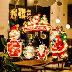 christmas decorations are hanging from the ceiling in front of a store window with santa clause on it