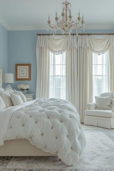 a white bed sitting next to a window in a bedroom under a chandelier