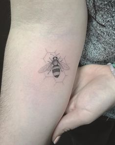 a small bee tattoo on the left side of the thigh, with hexagons