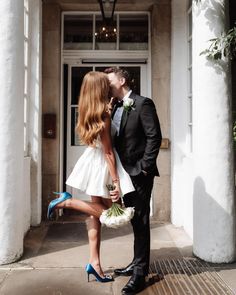 a man and woman kissing in front of a building