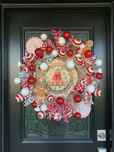 a christmas wreath with candy canes and ornaments hanging on the front door to welcome guests