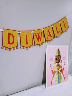 a diwali banner is hanging on the wall next to a card and photo