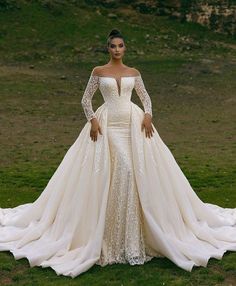 a woman in a wedding dress standing on the grass with her hands on her hips