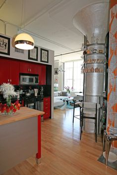 an open kitchen and dining room with red cabinets, wood flooring and stainless steel appliances