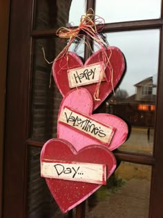 two heart shaped valentine's day decorations hanging from a window sill with the words happy valentine's day written on them