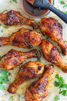 grilled chicken wings on parchment paper with dipping sauce in the bowl and parsley