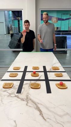 two men standing in front of a table with cookies on it