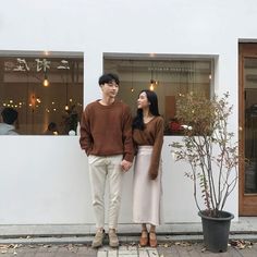 a man and woman standing next to each other in front of a building with windows