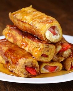 a white plate topped with pancakes covered in syrup and sausage wrapped in pastry wrappers