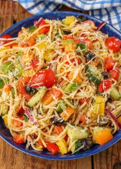 a blue bowl filled with pasta salad on top of a wooden table