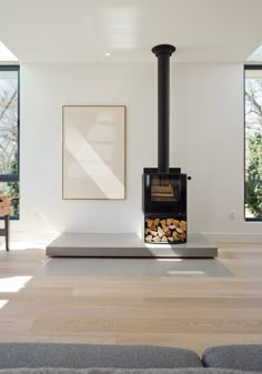 a living room with a fire place in the center and wood stacked on the floor