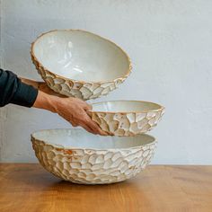 a person is holding two bowls in front of each other on a wooden counter top