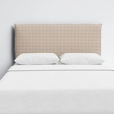 a bed with two pillows on it and a headboard made out of plaid fabric